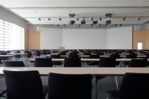 Spacious contemporary conference room with rows of tables and chairs, ready for meetings.